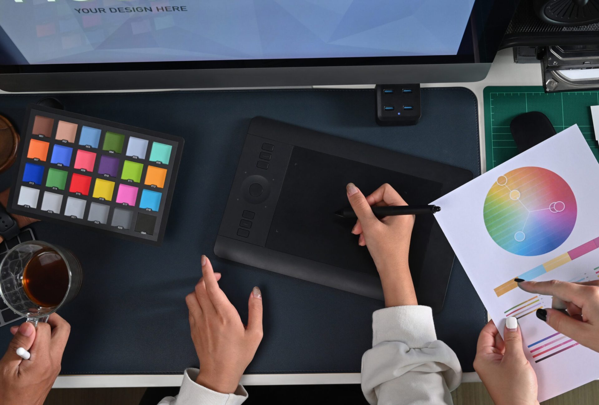Above view group of graphic designer working modern devices and color swatches at creative office.